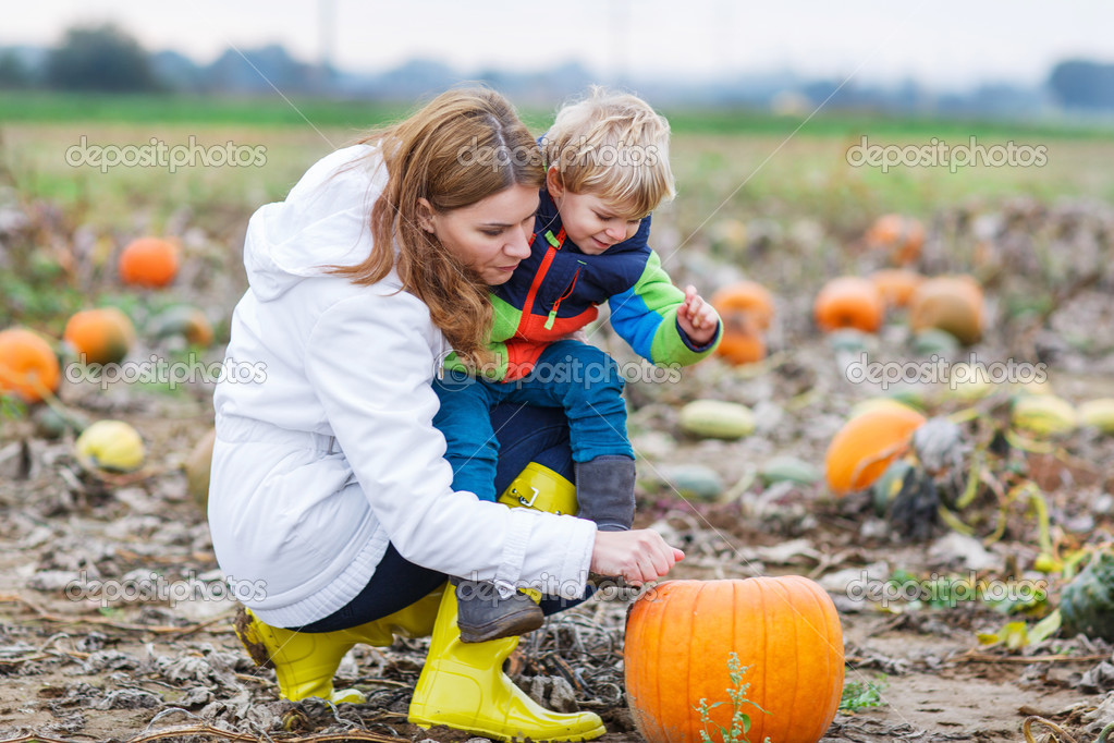 Mother and two little sons having fun on pumpkin patch.