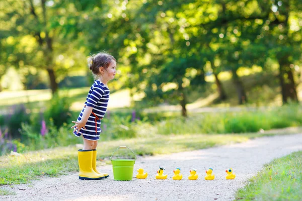 Adorável menina de 2 brincando com patos de borracha amarela em su — Fotografia de Stock