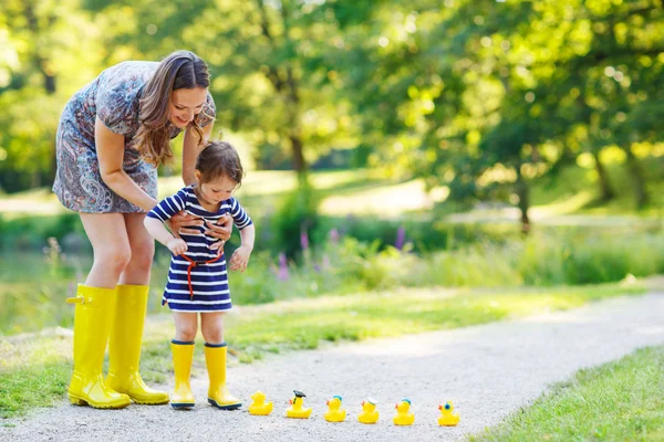 Mãe e pequena filha adorável em botas de borracha amarela — Fotografia de Stock