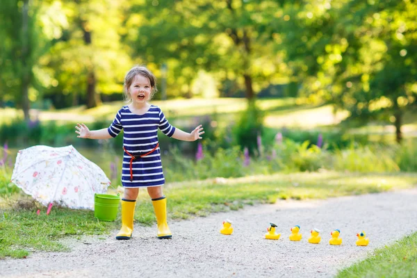 Двухлетняя девочка играет с желтыми резиновыми утятами — стоковое фото