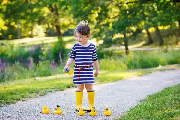Двухлетняя девочка играет с желтыми резиновыми утятами — стоковое фото