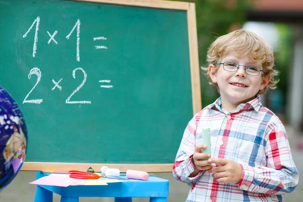 Lindo niño en pizarra practicando matemáticas —  Fotos de Stock