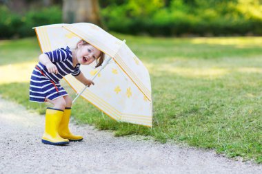 Sarı yağmur botları ve şemsiye summe içinde çok sevimli küçük bir çocuk