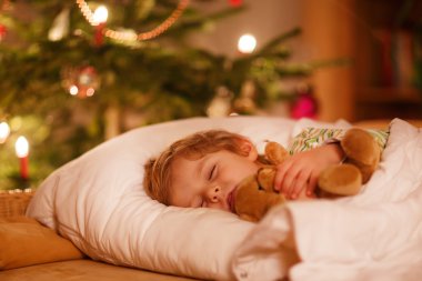 küçük şirin sarışın çocuk Noel ağacının altında uyuyor
