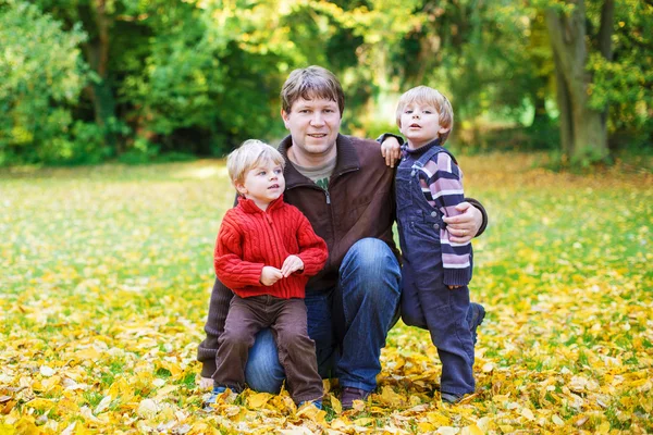 Pai feliz com seus filhos pequenos se divertindo no dia ensolarado do outono em — Fotografia de Stock