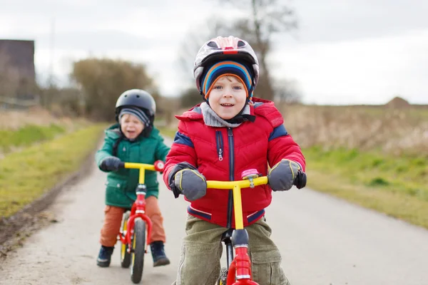 Two little twin toddler boys having fun on bicycles, outdoors — Stock Photo, Image