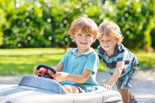 Zwei glückliche Geschwister spielen mit Spielzeugauto — Stockfoto