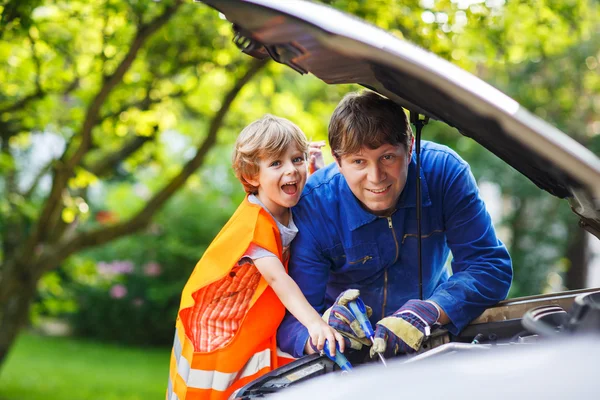 Young father teaching his little son to change motor oil in fami — Stock Photo, Image