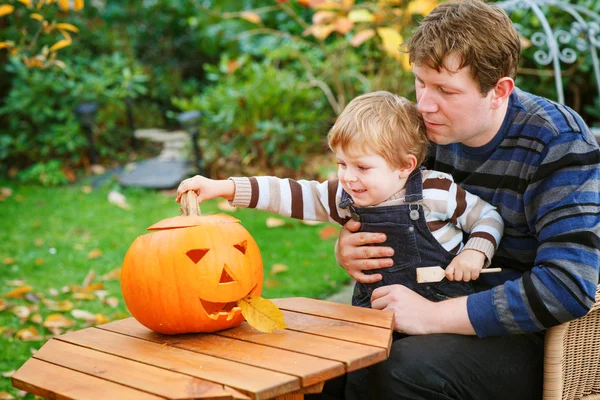 Jonge man en peuter jongen halloween pompoen maken — Stockfoto