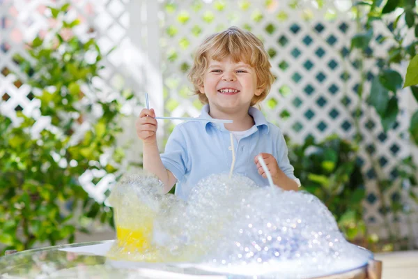 Menino feliz fazendo experiência com água colorida e sabão — Fotografia de Stock