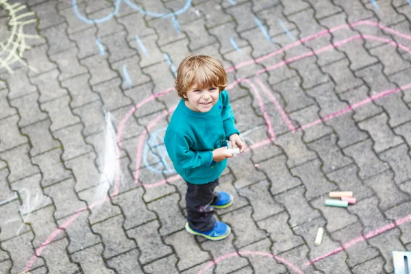 Kleine blonde jongen schilderen met kleurrijke krijtjes buitenshuis — Stockfoto