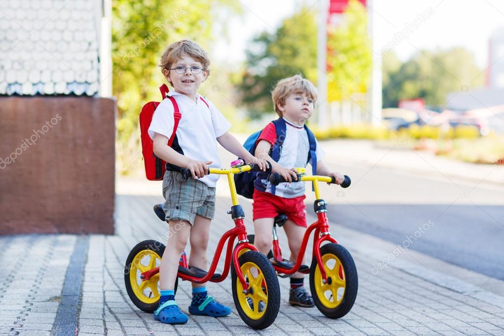 Two little siblings children having fun on bikes in city, outdoo