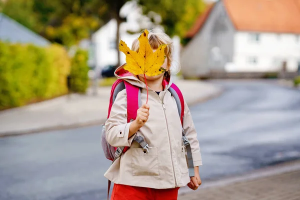 最初の日にかわいい幼児の女の子が学校に遊びに行く。健康な幸せな子供が保育園に歩いています。バックパックを持つ子供は街の通りで一日ケアに行く屋外で — ストック写真