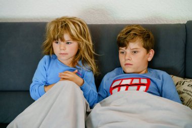 Sevimli küçük anaokulu kızı ve liseli çocuk televizyonda hayvan filmi ya da film izliyor. Pijamalı mutlu sağlıklı çocuklar, kardeşler birlikte eğleniyor..