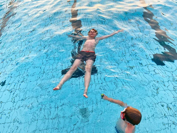 Zwei Schulkinder spielen und planschen an einem warmen Sommertag in einem Freibad. Glückliche gesunde Kinder genießen das sonnige Wetter im städtischen Freibad. Aktivitäten für Kinder im Freien mit Wasser. — Stockfoto