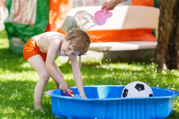 Маленький мальчик-малыш веселится с брызгами воды в летней гаре — стоковое фото