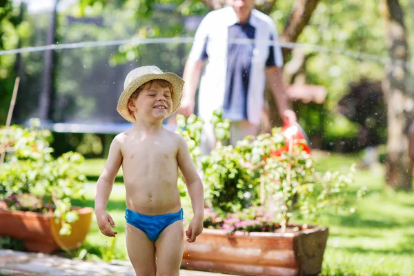 Little toddler boy having fun with splashing water in summer gar — Stock Photo, Image