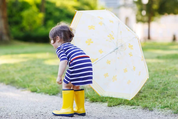 Adorable niño pequeño en botas de lluvia amarillas y paraguas en summe —  Fotos de Stock