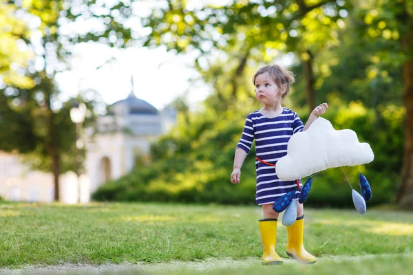 Niedliches Kleinkind in gelben Gummistiefeln und Spielzeug mit Regentropfen — Stockfoto