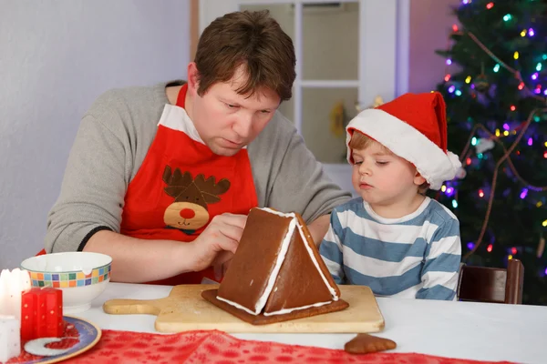 Pai e filho se preparando uma casa de biscoito de gengibreOjciec i syn trochę przygotowania piernika cookie — Zdjęcie stockowe