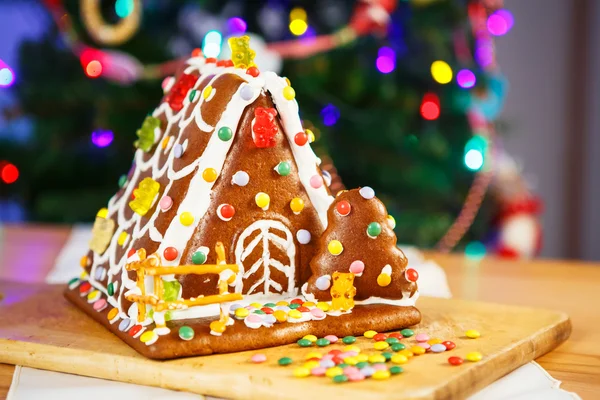 Maison en pain d'épice avec arbre de Noël et lumières sur le fond . — Photo