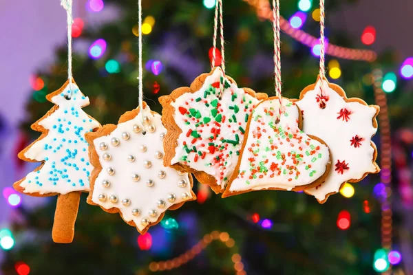 Peperkoek cookies opknoping met kerstboom op achtergrond. — Stockfoto