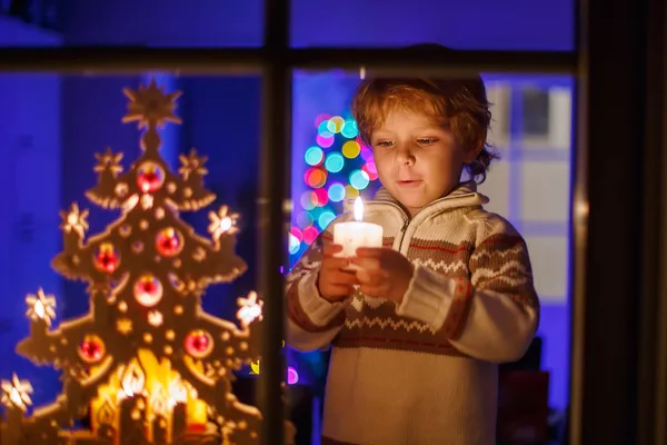 Anak kecil berdiri dekat jendela pada saat Natal — Stok Foto