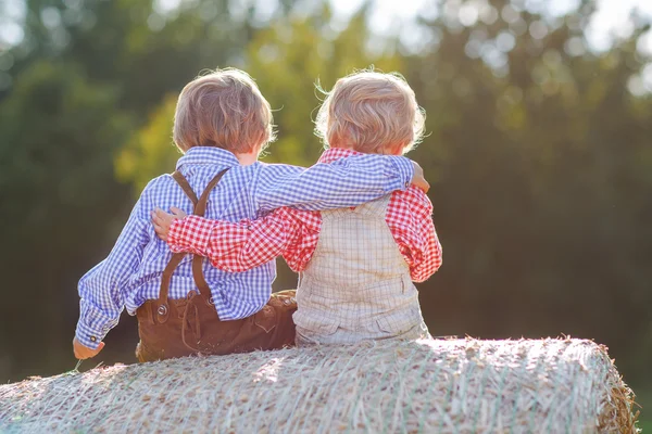 Deux petits amis assis sur une balle de foin — Photo