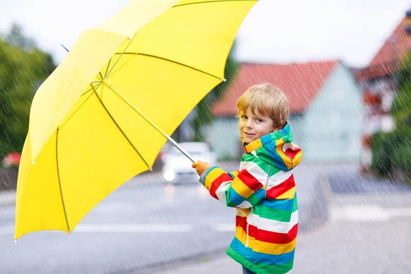 Adorabile bambino con ombrello giallo e giacca colorata — Foto Stock
