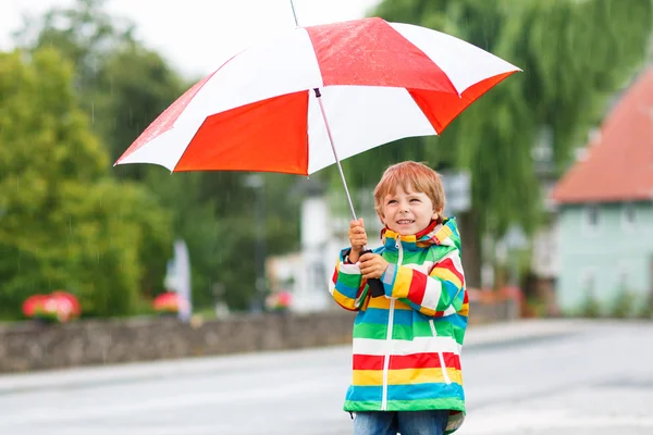 Beautiful child with yellow umbrella and colorful jacket outdoor — Stock Photo, Image
