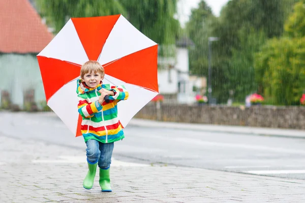 Hermoso niño con paraguas amarillo y chaqueta colorida al aire libre —  Fotos de Stock