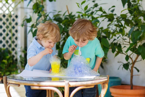 Två glada syskon pojkar att göra experiment med färgglada bubblor — Stockfoto