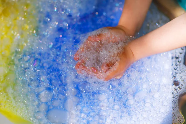 Handen van kind spelen met kleurrijke zeepbellen. — Stockfoto