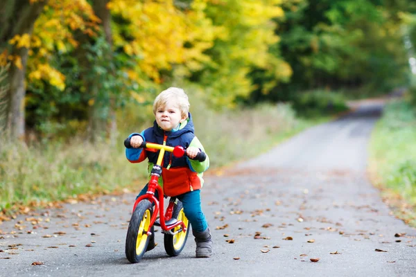 Carino attivo bambino guida sulla sua moto nella foresta autunnale — Foto Stock