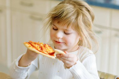 Sevimli küçük kız İtalyan pizzasını sebze ve peynirle yiyor. Mutlu çocuk taze pişmiş sağlıklı yemek yiyor. Domatesli, mısırlı ve sebzeli. Evde, evde..
