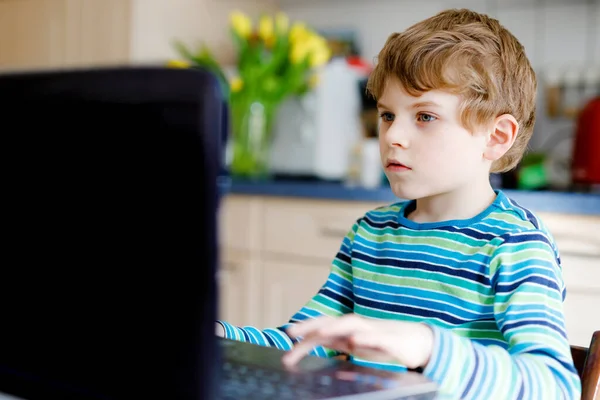 Grabben lär sig hemma på laptop för skolan. Grundskolebarn som gör läxor och använder anteckningsblock och moderna prylar. Hemskolekoncept. Att ha en videolektion med lärare. — Stockfoto