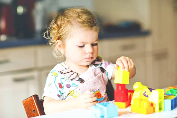 Schattig peutermeisje dat speelt met educatief speelgoed in de kinderkamer. Gelukkig gezond kind hebben plezier met kleurrijke verschillende plastic blokken thuis. Schattig baby leren maken en bouwen. — Stockfoto