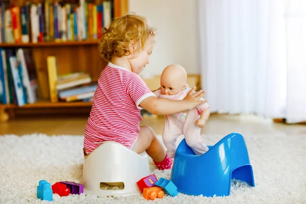 Gros plan de mignon petit enfant de 12 mois bébé fille assis sur pot. Enfant jouant avec un jouet de poupée. Concept de formation aux toilettes. Apprentissage des bébés, étapes de développement — Photo