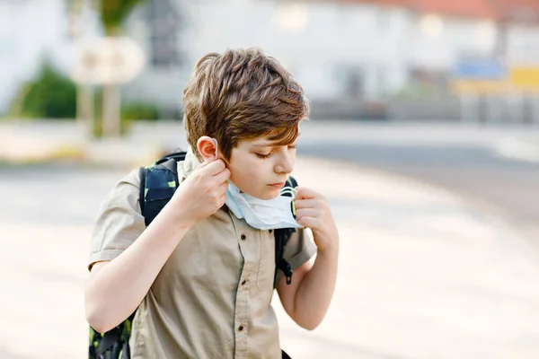 Szczęśliwy chłopiec w okularach i masce medycznej z powodu pandemii wywołanej wirusem korony. Uczennica z torbą czeka na autobus w drodze do szkoły w słoneczny dzień. Zdrowe dziecko na ulicy. — Zdjęcie stockowe