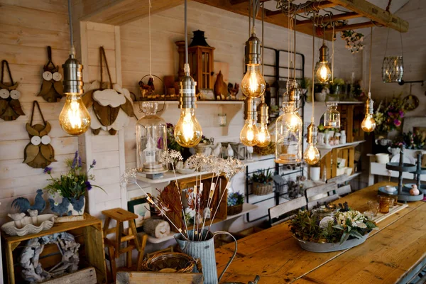 Beautiful arrangement of wooden decor and ceramic decoration in a shop for indoor, outdoor and garden. Light bulb as fairy lights. — Stock Photo, Image