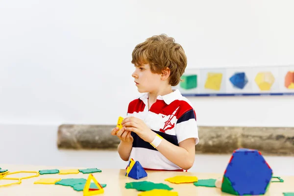 Niño feliz divirtiéndose con la construcción y creación de figuras geométricas, el aprendizaje de las matemáticas y la geometría —  Fotos de Stock