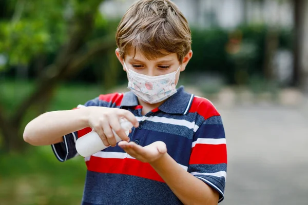 Шкільний хлопчик з медичною маскою як захист від пандемії коронавірусної хвороби. Дитина тримає пляшку з дезінфікуючим засобом для чищення рук. захисне обладнання проти ковадла — стокове фото
