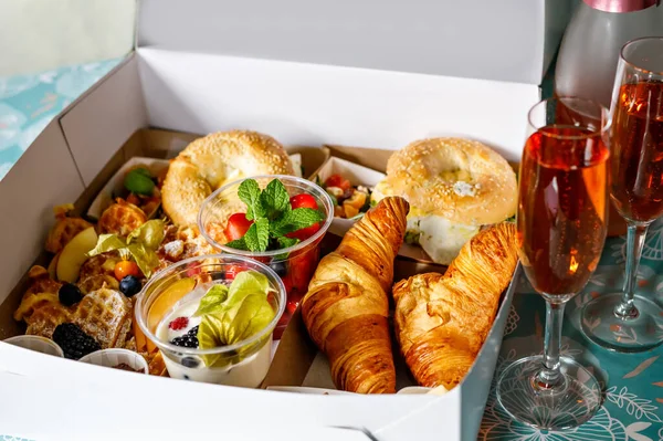 Breakfast in a box to go from closed restaurant due corona virus lockdown. Fresh bagels, croissants, berries, salad and vegetables for romantic lunch. Food to go for picnic.