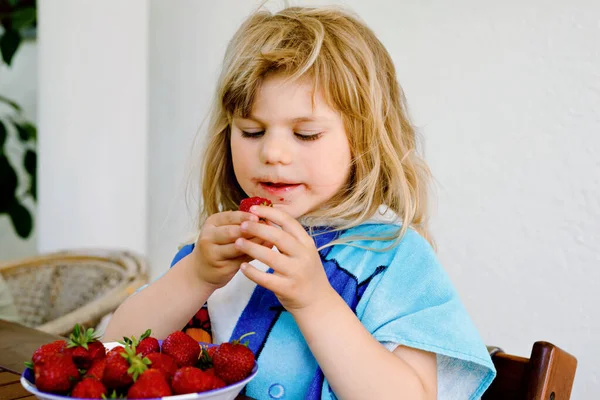 学龄前小女孩吃新鲜草莓。可爱的婴儿品尝和咀嚼成熟的草莓.健康的食物、童年和发展。快乐的孩子在家里或托儿所. — 图库照片