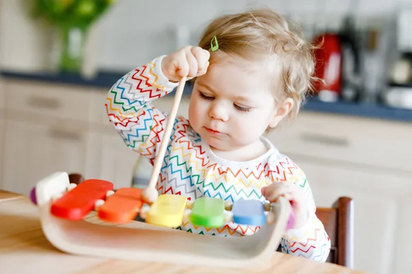 Adorable linda y hermosa niña jugando con un juguete educativo de música de madera en casa. Feliz niño emocionado aprender a jugar colorido xilofón arco iris. Educación temprana, actividad para los niños. —  Fotos de Stock