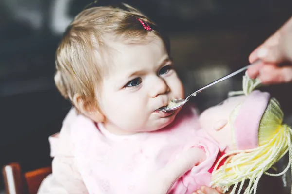 可爱的女婴用勺子、捣碎的蔬菜和浓汤吃饭。食物，儿童，食物和人的概念-可爱的幼儿，女儿，勺子坐在高椅子上，在家吃饭. — 图库照片