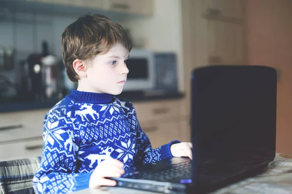 Ensamstående pojke lär sig hemma på laptop för skolan. Bedårande barn gör läxor och använder anteckningsbok och moderna prylar. Hemskolekoncept under pandemisk karantän mot koronavirus — Stockfoto