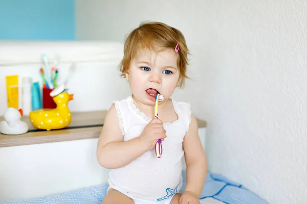 Mała dziewczynka trzymająca szczoteczkę i myjąca pierwsze zęby. Maluch uczy się czyścić zęby mleka. — Zdjęcie stockowe