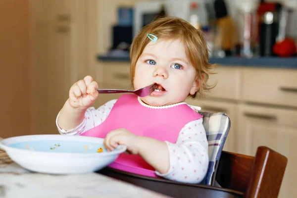 Entzückendes kleines Mädchen, das aus einem Löffel püriertem Gemüse und Püree isst. Ernährungs-, Kinder-, Ernährungs- und Personenkonzept — Stockfoto