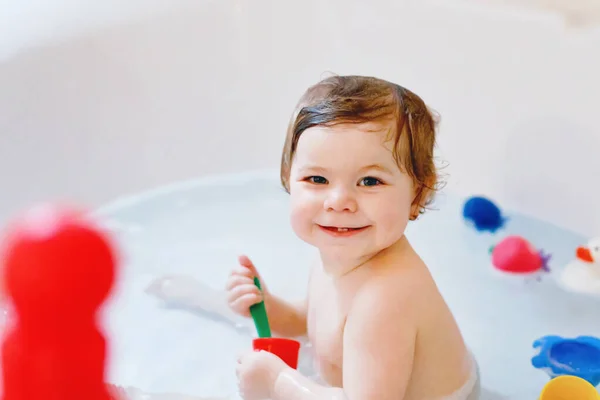 Schattig schattig baby meisje neemt schuimig bad in bad. Peuter spelen met bad rubber speelgoed. — Stockfoto